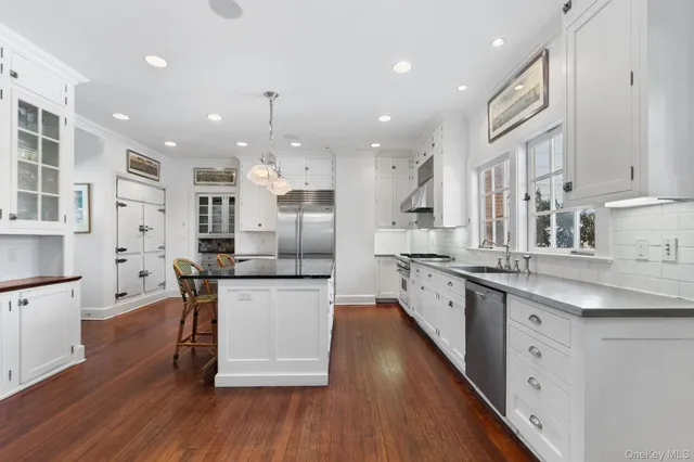 a kitchen with stainless steel appliances kitchen island granite countertop wooden floors and white cabinets