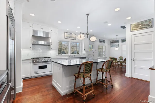 a kitchen with stainless steel appliances a dining table chairs stove and cabinets