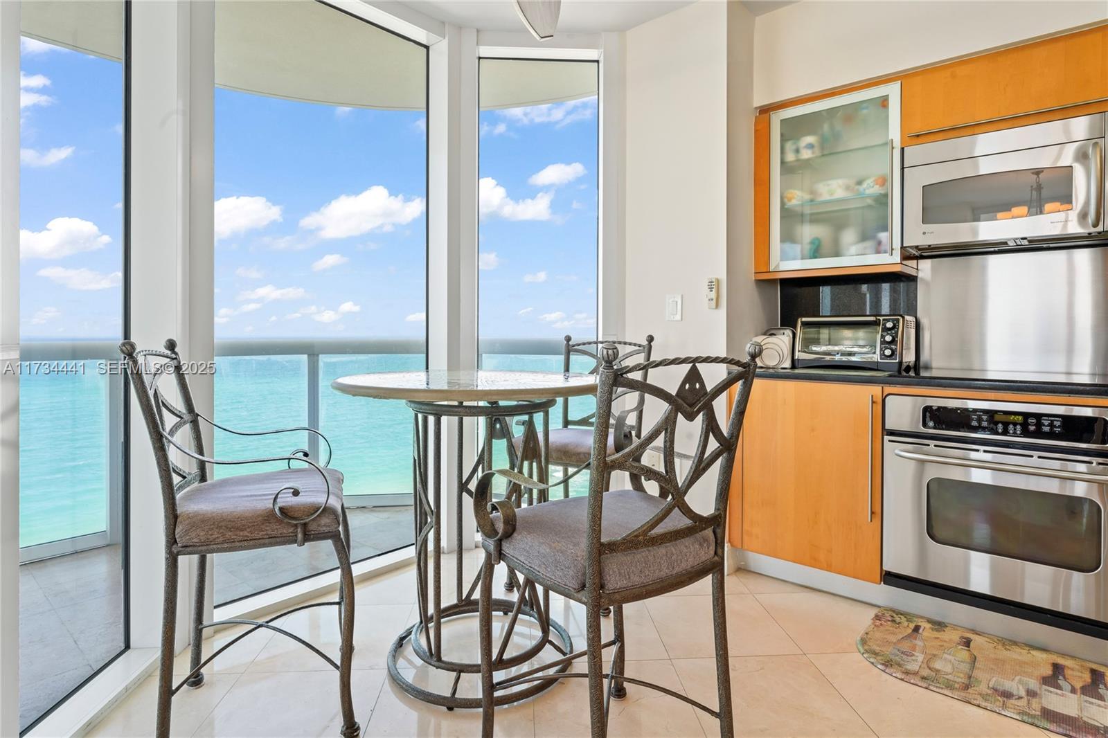 6365 Collins Avenue, Unit 1901 Miami Beach, FL 33141 - Photo 16 of 84 a view of a dining room with furniture next to a large window and kitchen view
