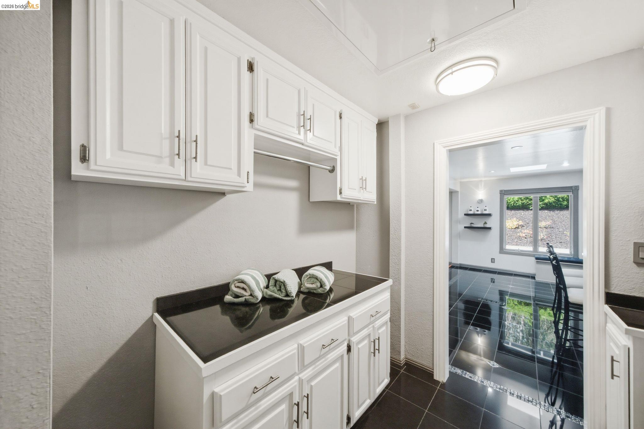 11133 Golf Links Road Oakland, CA 94605 - Photo 23 of 57 White cabinetry with brushed nickel hardware, black countertop, and black tile flooring