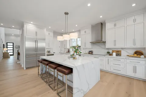 a kitchen with stainless steel appliances granite countertop a sink a stove a refrigerator and island with wooden floor