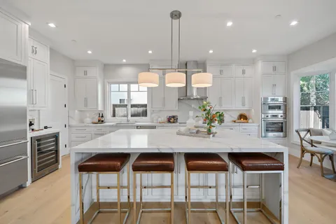 a kitchen with stainless steel appliances kitchen island granite countertop a kitchen island and chairs in it