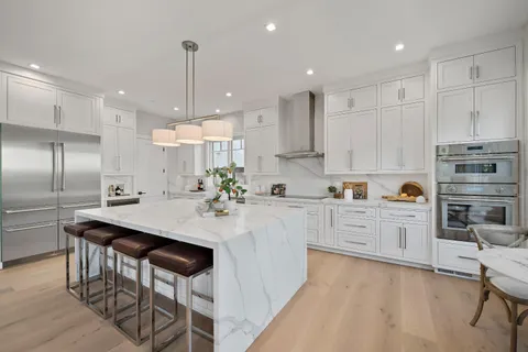 a kitchen with kitchen island granite countertop a sink center island stainless steel appliances and cabinets