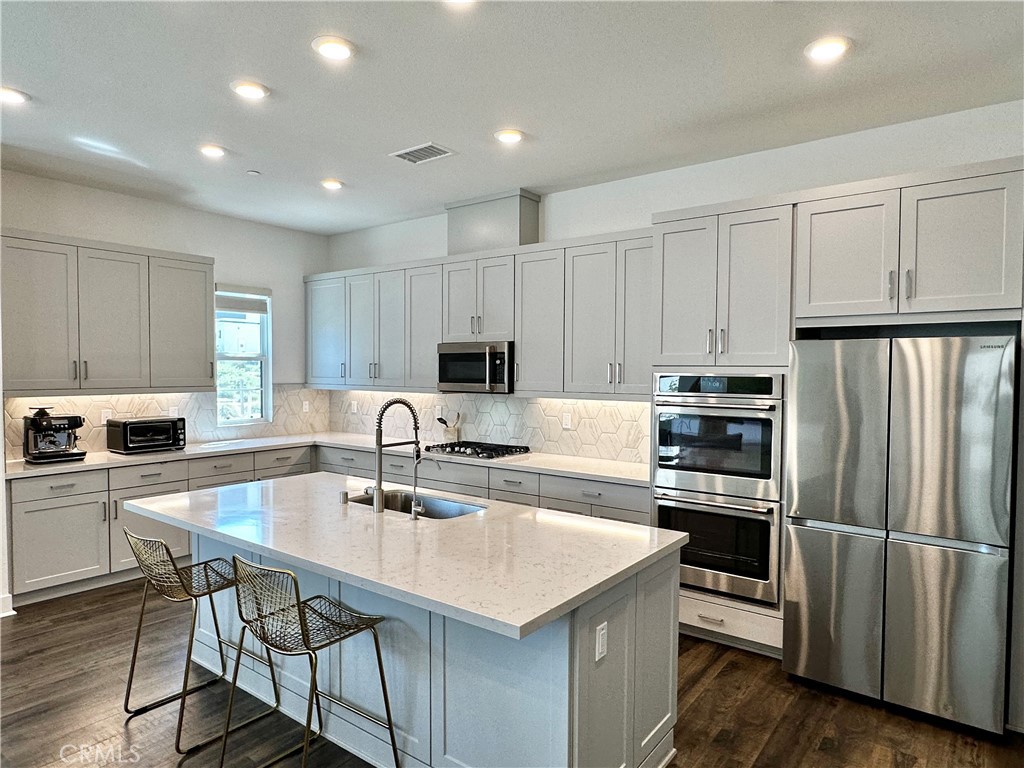 124 Yugen Irvine, CA 92618 - Photo 8 of 31 a kitchen with kitchen island a white counter top space cabinets and stainless steel appliances