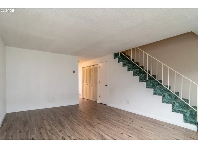 a view of an empty room with stairs and wooden floor