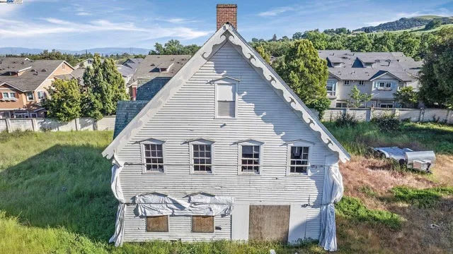 a aerial view of a house next to a yard with plants and lake view