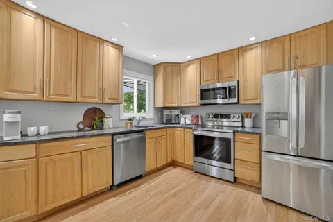 a kitchen with stainless steel appliances granite countertop a refrigerator a stove top oven a sink and dishwasher with wooden floor