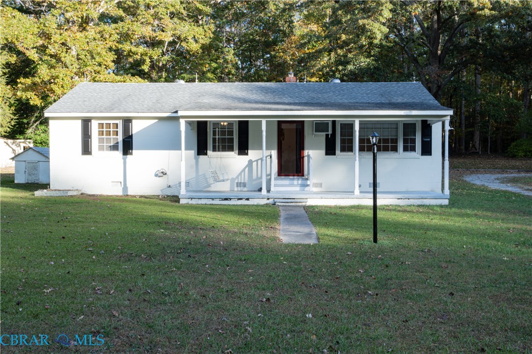 Single story home with covered porch, a front yard, and a shingled roof
