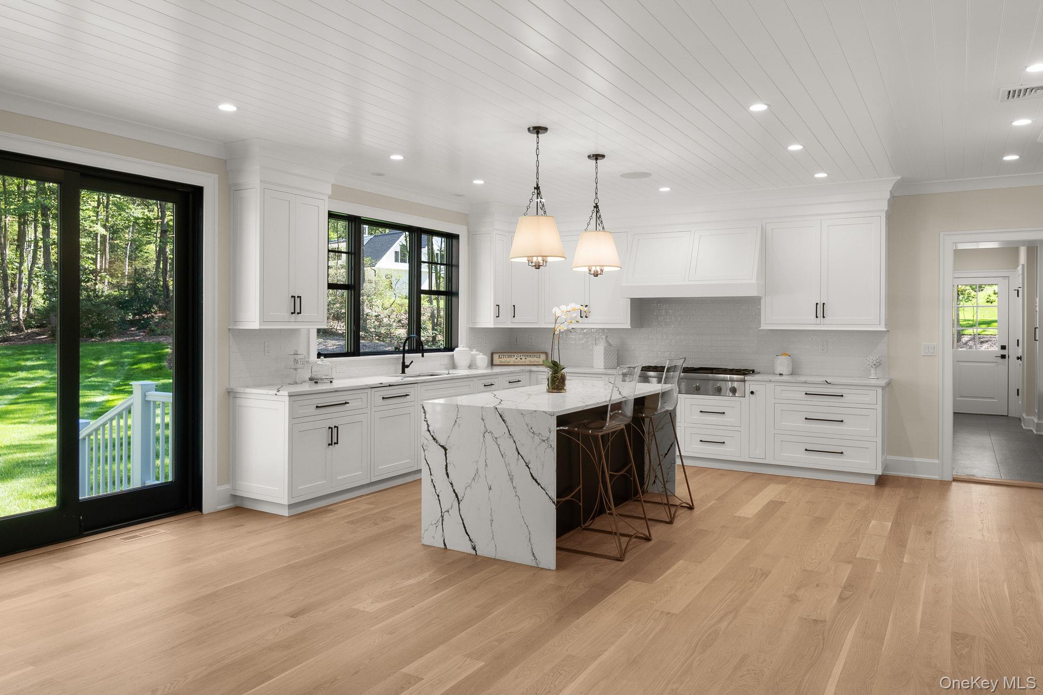 64 Saw Mill Road Cold Spring Harbor, NY 11724 - Photo 13 of 50 a large kitchen with kitchen island granite countertop a stove a sink a refrigerator and white cabinets with wooden floor