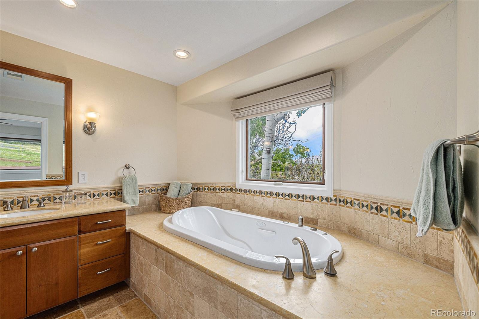 8 Blue Grouse Ridge Road Littleton, CO 80127 - Photo 23 of 49 a bathroom with a tub a sink a mirror and a window