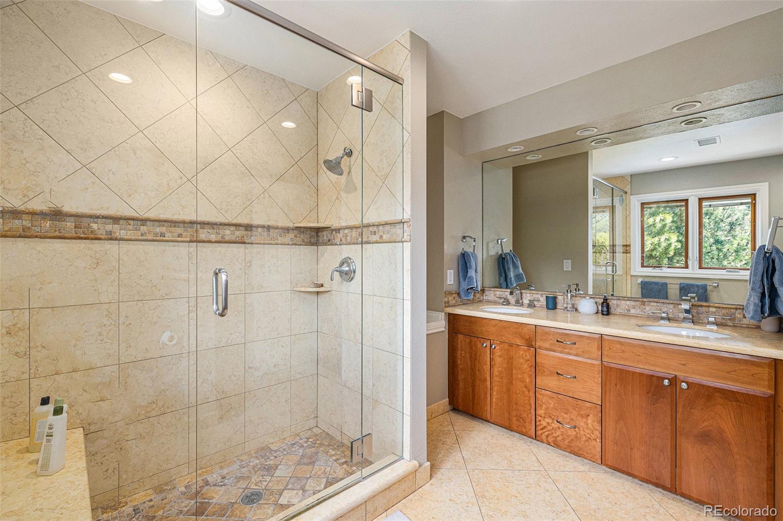 8 Blue Grouse Ridge Road Littleton, CO 80127 - Photo 29 of 49 a bathroom with a double vanity sink a mirror and a shower