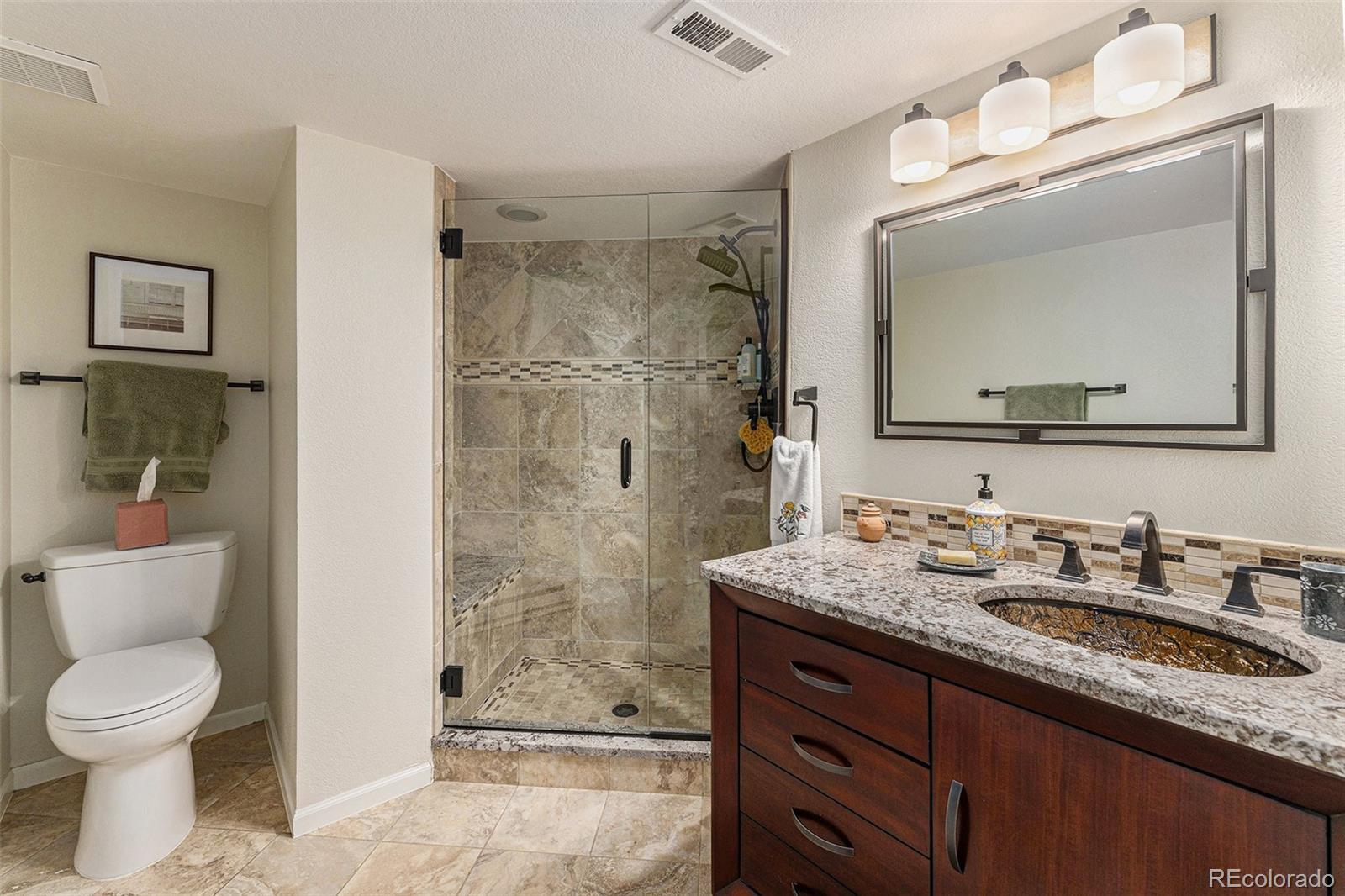 8 Blue Grouse Ridge Road Littleton, CO 80127 - Photo 37 of 49 a bathroom with a granite countertop sink toilet a large mirror and shower