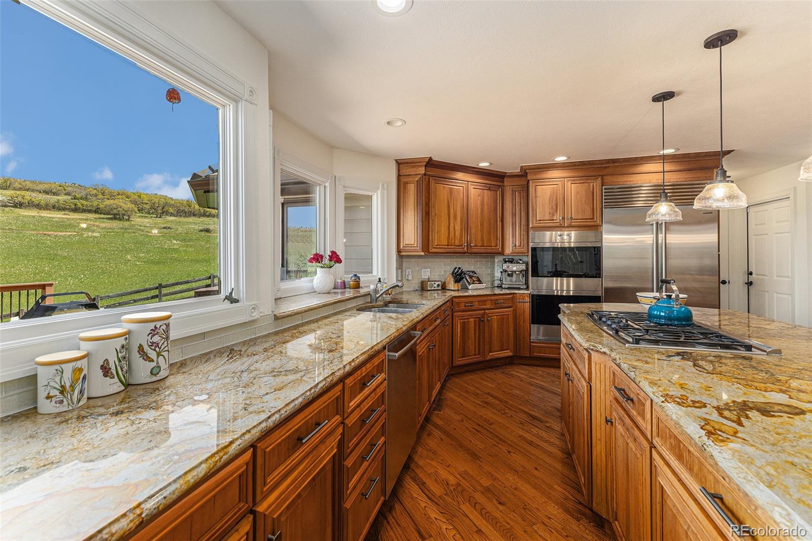 8 Blue Grouse Ridge Road Littleton, CO 80127 - Photo 7 of 49 a large kitchen with kitchen island granite countertop a large window and stainless steel appliances
