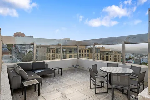 a roof deck with a table and chairs and potted plants