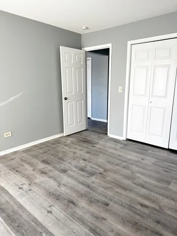 an empty room with wooden floor & closet area
