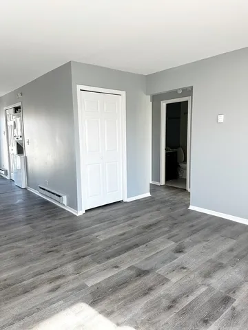 a view of an empty room with wooden floor and closet