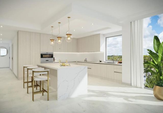 a large white kitchen with kitchen island a chandelier a stove a dining table and chairs