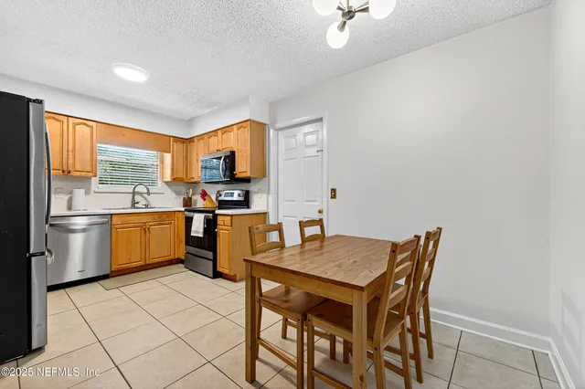 a kitchen with granite countertop a stove a sink a dining table and chairs