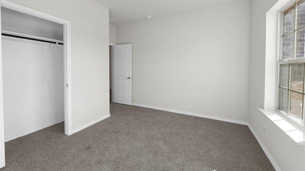 412 Carthage Street Caddo Mills, TX 75135 - Photo 7 of 32 Carpeted room featuring a white interior door, a window with grid patterns, a built-in closet with hanging rod, and light-toned walls with baseboards