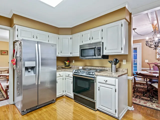 a kitchen with stainless steel appliances granite countertop a stove a refrigerator and white cabinets