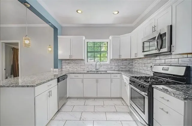 a kitchen with granite countertop white cabinets white stainless steel appliances with a sink and dishwasher