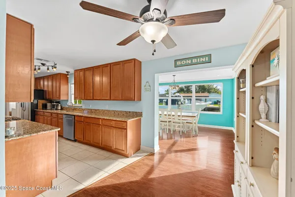 a open kitchen with stainless steel appliances granite countertop a stove top oven a refrigerator a sink and a dining table with wooden floor