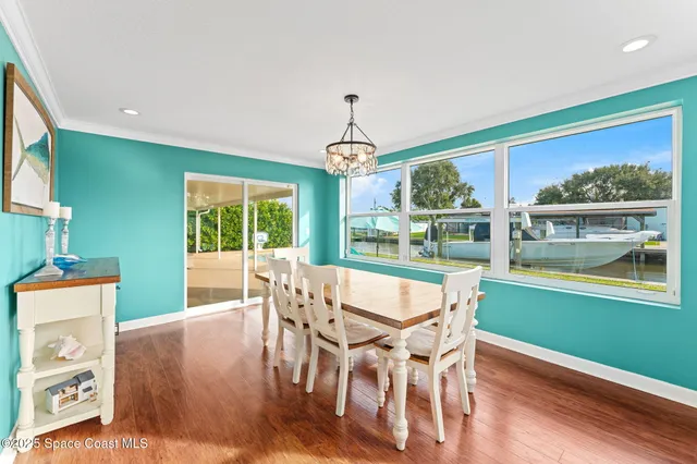 a dining room with wooden floor a chandelier a wooden table and chairs