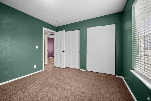 2095 South Main Street, Unit 13 Bountiful, UT 84010 - Photo 18 of 45 Unfurnished bedroom with two closets, carpet flooring, a textured wall, and a textured ceiling