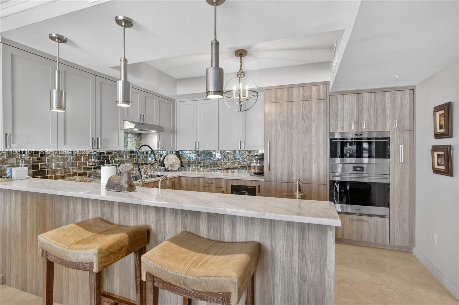100 South Birch Road, Unit 1103F Fort Lauderdale, FL 33316 - Photo 30 of 80 Spectacular kitchen w/ custom bleached walnut veneer cabinetry by renowned Chicago based millworker. Grain matches from top to bottom. Taj mahal quartzite. Wolf induction cooktop & double oven (w/ microwave / convenction at top oven), Sub Zero Refrigerator & Beverage Cooler, Miele Dishwasher. Counter seating. Antiqued mirror backsplash