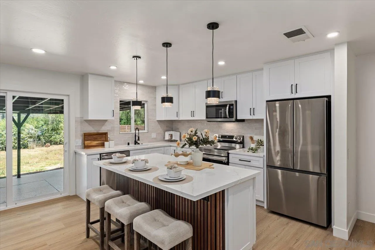 30118 Miller Road Valley Center, CA 92082 - Photo 6 of 75 a kitchen that has a lot of cabinets a sink a stove a refrigerator and a dining table with wooden floor
