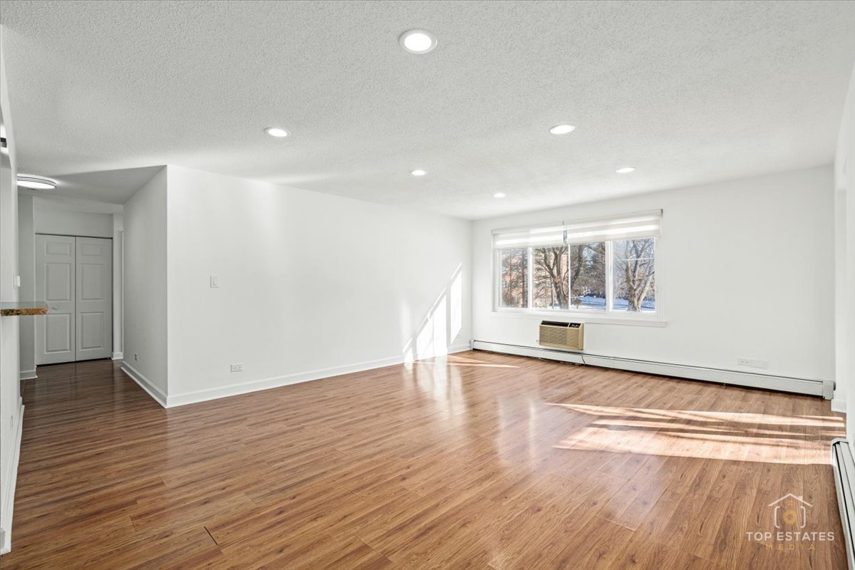 1107 South Old Wilke Road, Unit 208 Rolling Meadows, IL 60005 - Photo 11 of 43 an empty room with wooden floor and windows