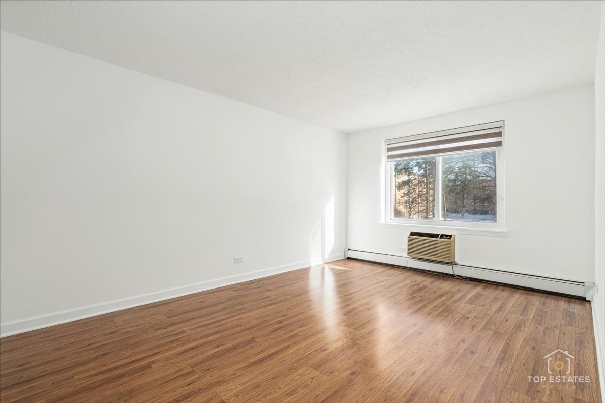 1107 South Old Wilke Road, Unit 208 Rolling Meadows, IL 60005 - Photo 23 of 43 a view of an empty room with wooden floor and a window