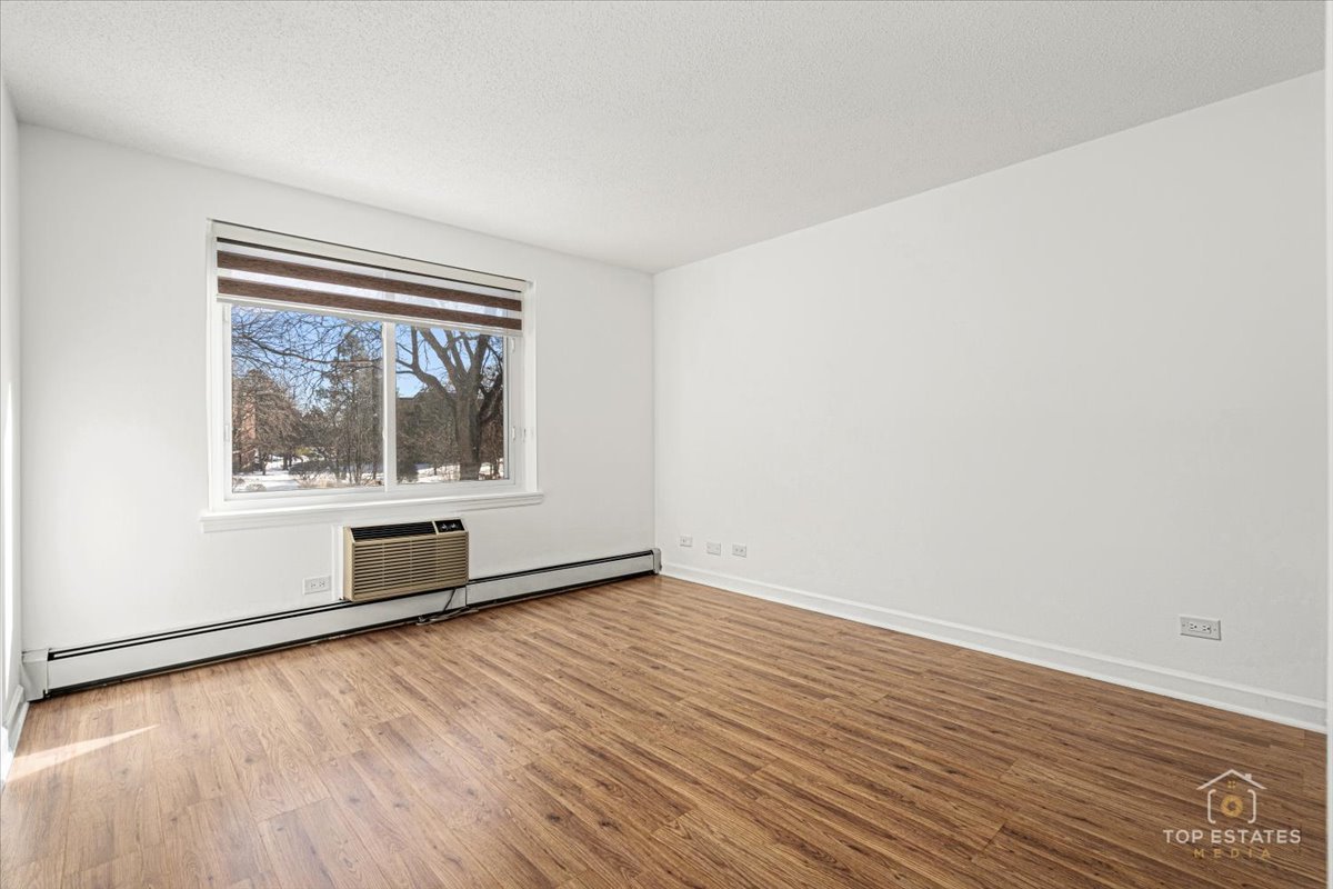 1107 South Old Wilke Road, Unit 208 Rolling Meadows, IL 60005 - Photo 29 of 43 an empty room with wooden floor and windows