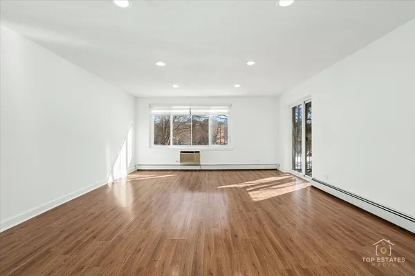 a view of a big room with wooden floor and windows