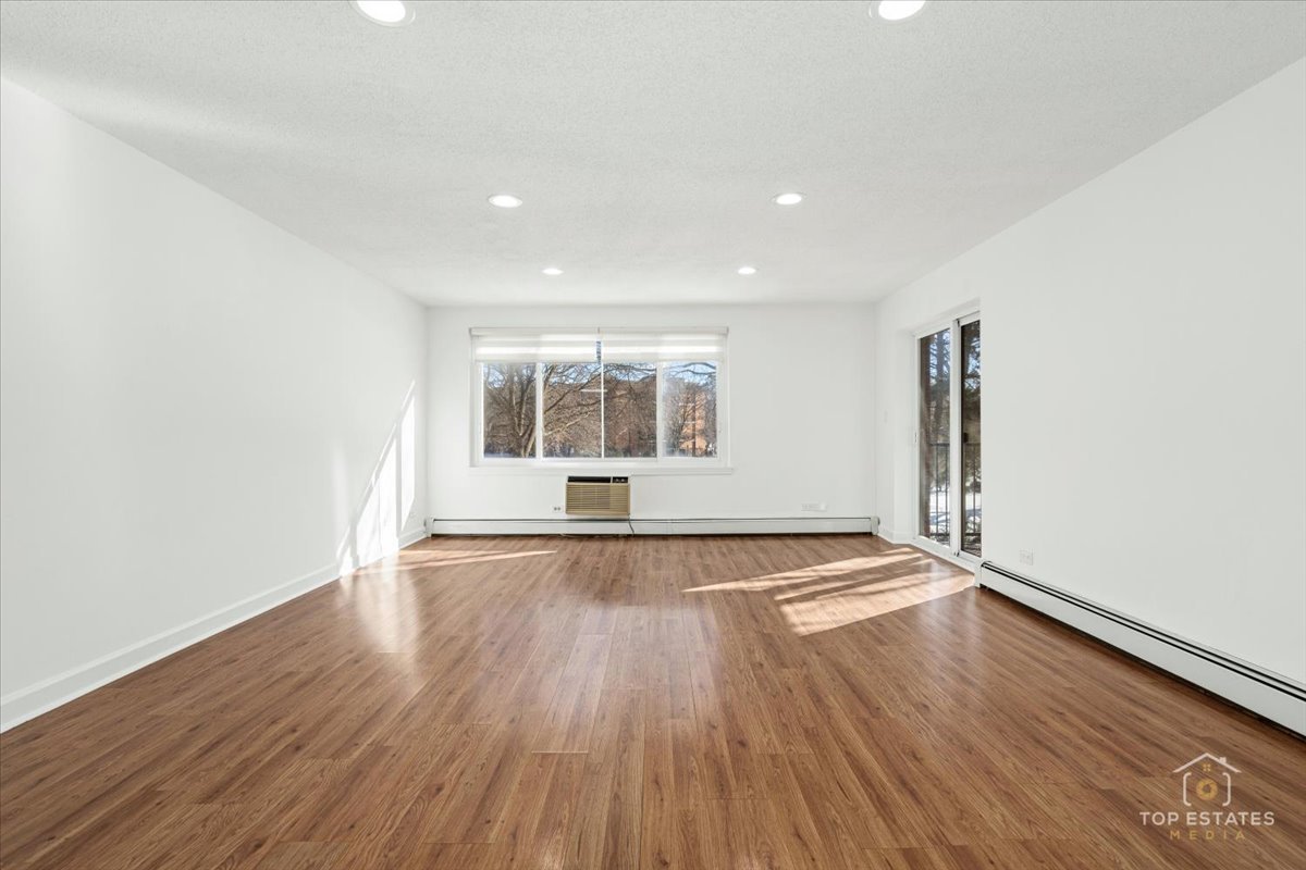 1107 South Old Wilke Road, Unit 208 Rolling Meadows, IL 60005 - Photo 10 of 43 an empty room with wooden floor and windows