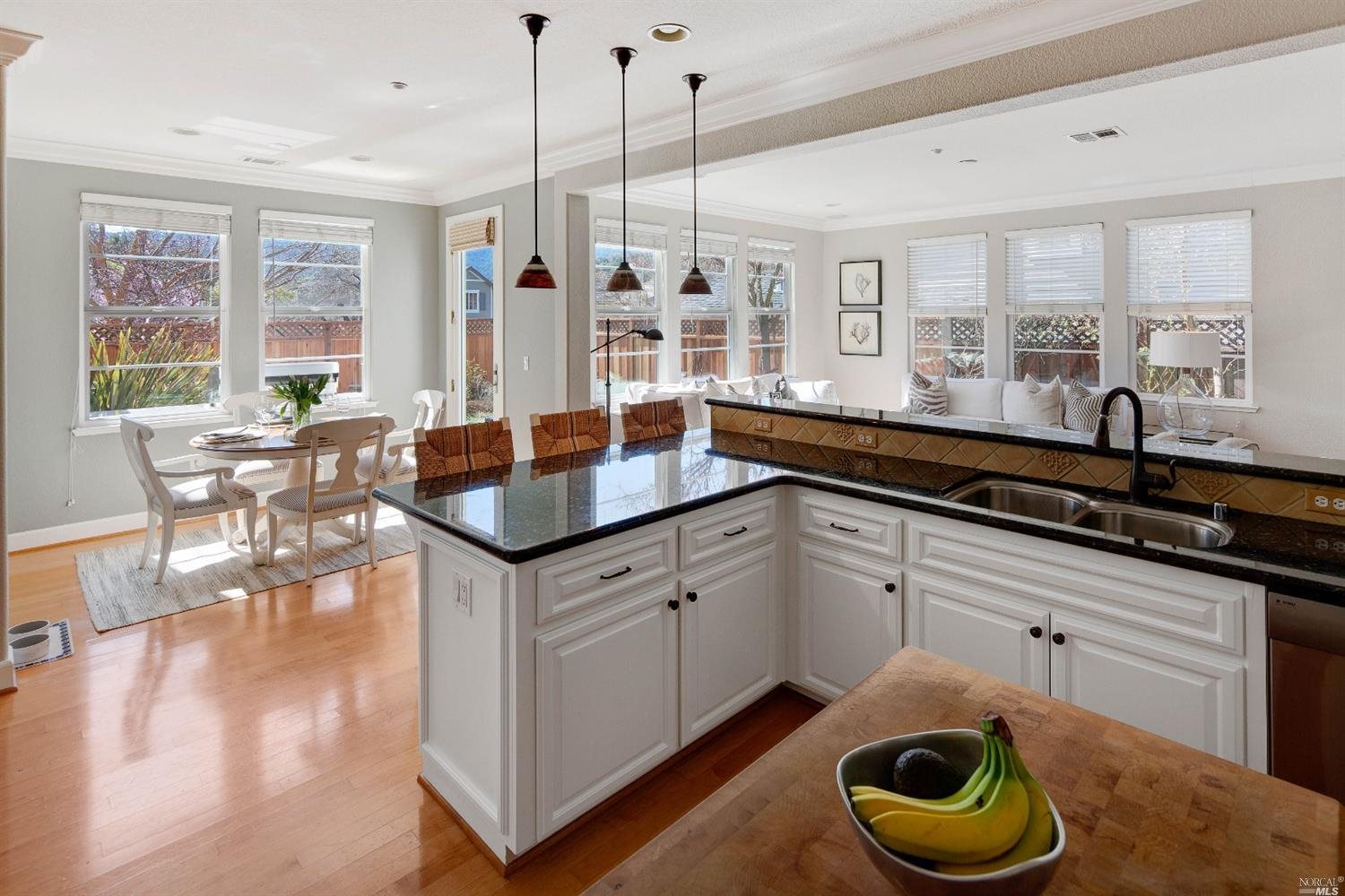 a kitchen with stainless steel appliances granite countertop a stove a sink and a dining table with white cabinets