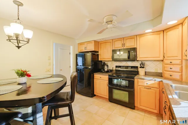 a kitchen with stainless steel appliances a stove a sink refrigerator and a dining table