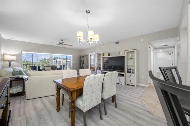 a dining room with wooden floor a chandelier a wooden table and chairs