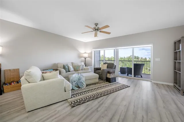 a living room with furniture large windows and wooden floor