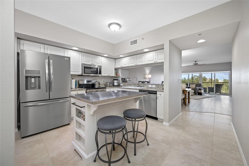960 Starkey Road, Unit 5504 Largo, FL 33771 - Photo 7 of 46 a kitchen with stainless steel appliances granite countertop a refrigerator a stove a sink a dining table and chairs