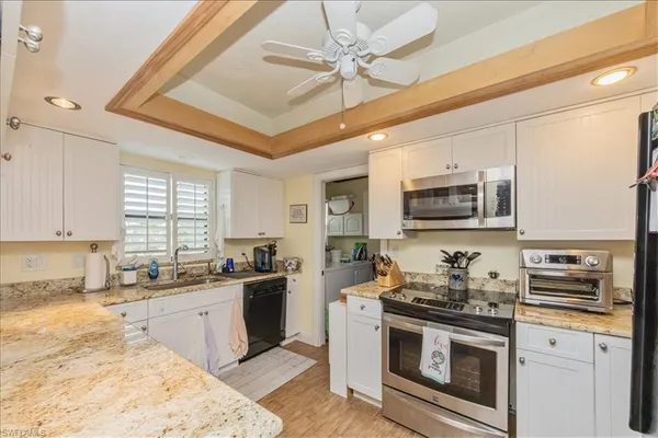 a kitchen with stainless steel appliances granite countertop a sink a stove a microwave a refrigerator cabinets and a window