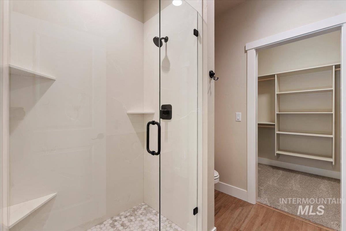 1300 Birch Street Parma, ID 83660 - Photo 12 of 24 Bathroom with a shower stall, a walk in closet, and light wood-type flooring