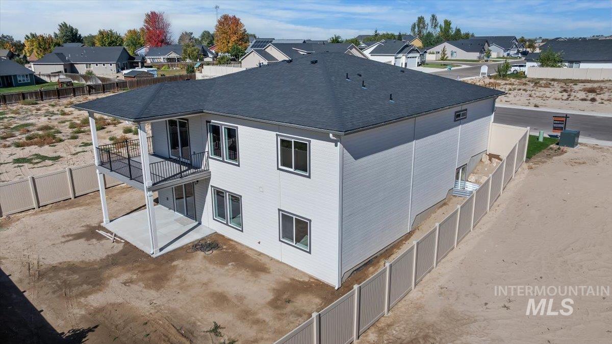 1300 Birch Street Parma, ID 83660 - Photo 18 of 24 View of side of home with a fenced backyard, a patio area, a shingled roof, a residential view, and a balcony