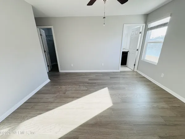 a view of an empty room with wooden floor and a window