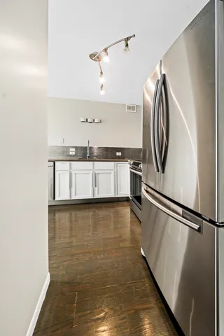 a view of a kitchen with a sink and dishwasher a refrigerator with wooden floor