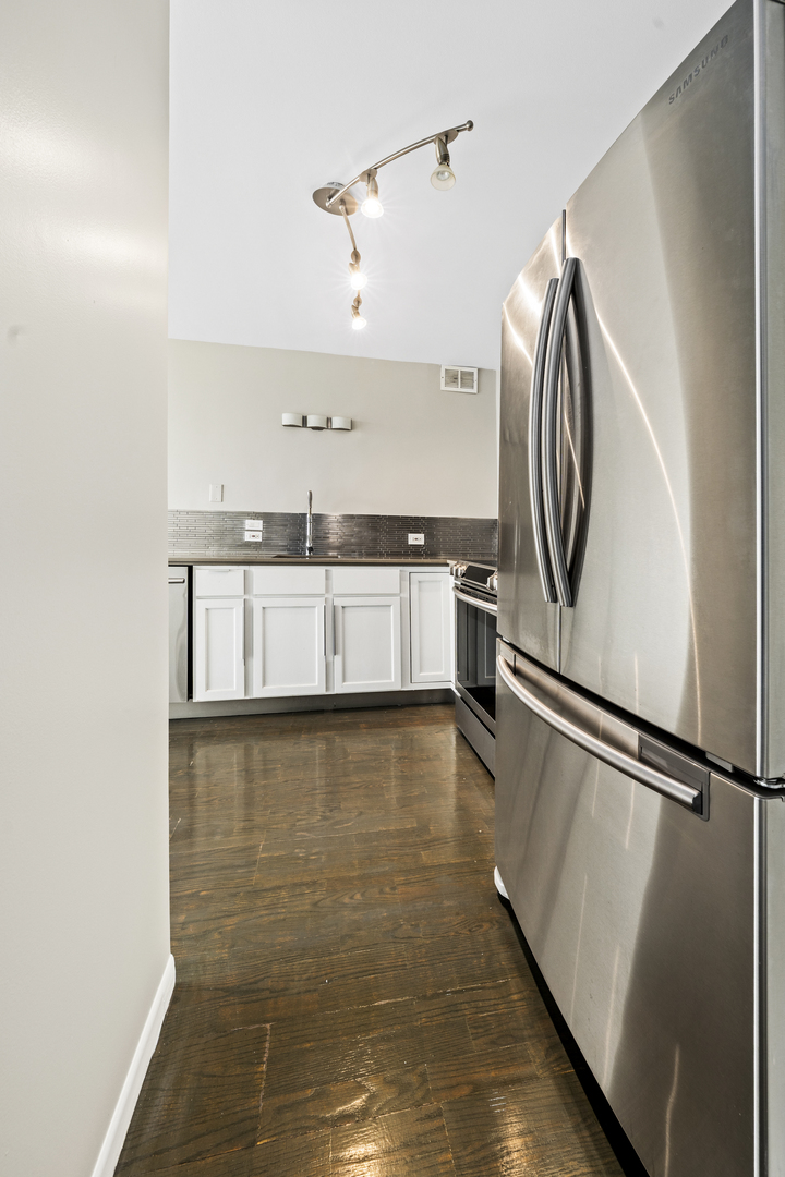 1540 North LaSalle Street, Unit 907 Chicago, IL 60610 - Photo 10 of 16 a view of a kitchen with a sink and dishwasher a refrigerator with wooden floor