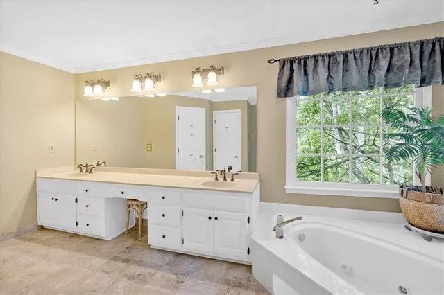 a spacious bathroom with a tub sink and mirror