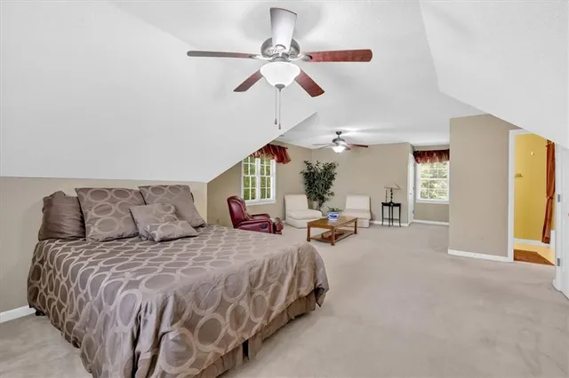 a spacious bedroom with a bed couch and ceiling fan