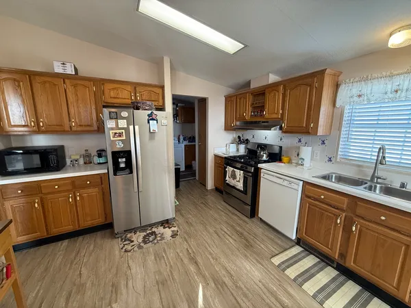 a kitchen with stainless steel appliances granite countertop a refrigerator a sink dishwasher a stove with wooden cabinets and floor