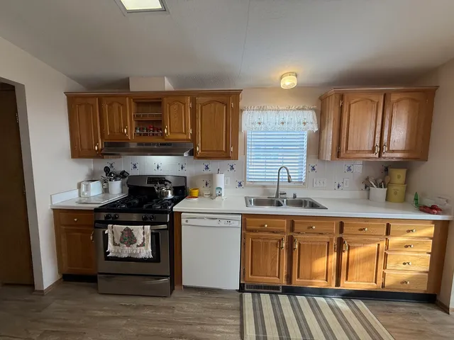a kitchen with stainless steel appliances granite countertop a stove a sink dishwasher and a microwave oven with wooden cabinets